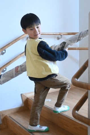 こども園の階段で物を運ぶ園児