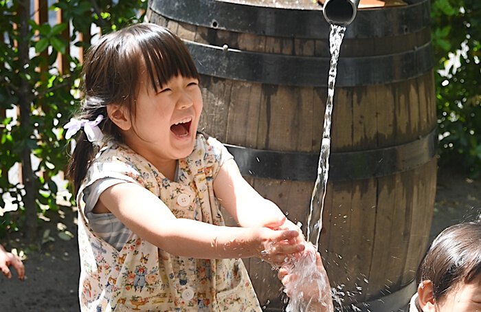 園庭で水遊びをする笑顔の園児